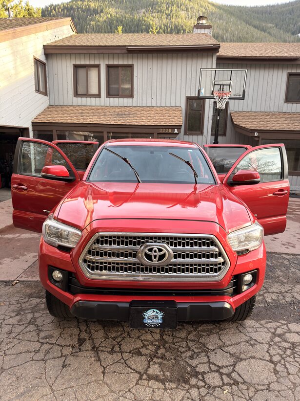 Red Toyota Tacoma with doors open after a full detail